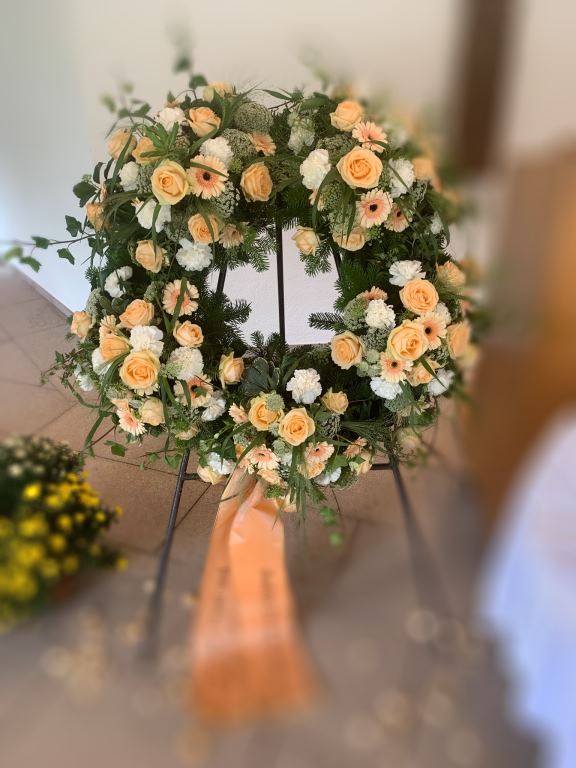 Trauerkranz in Apricot auf einem Ständer mit Schleife